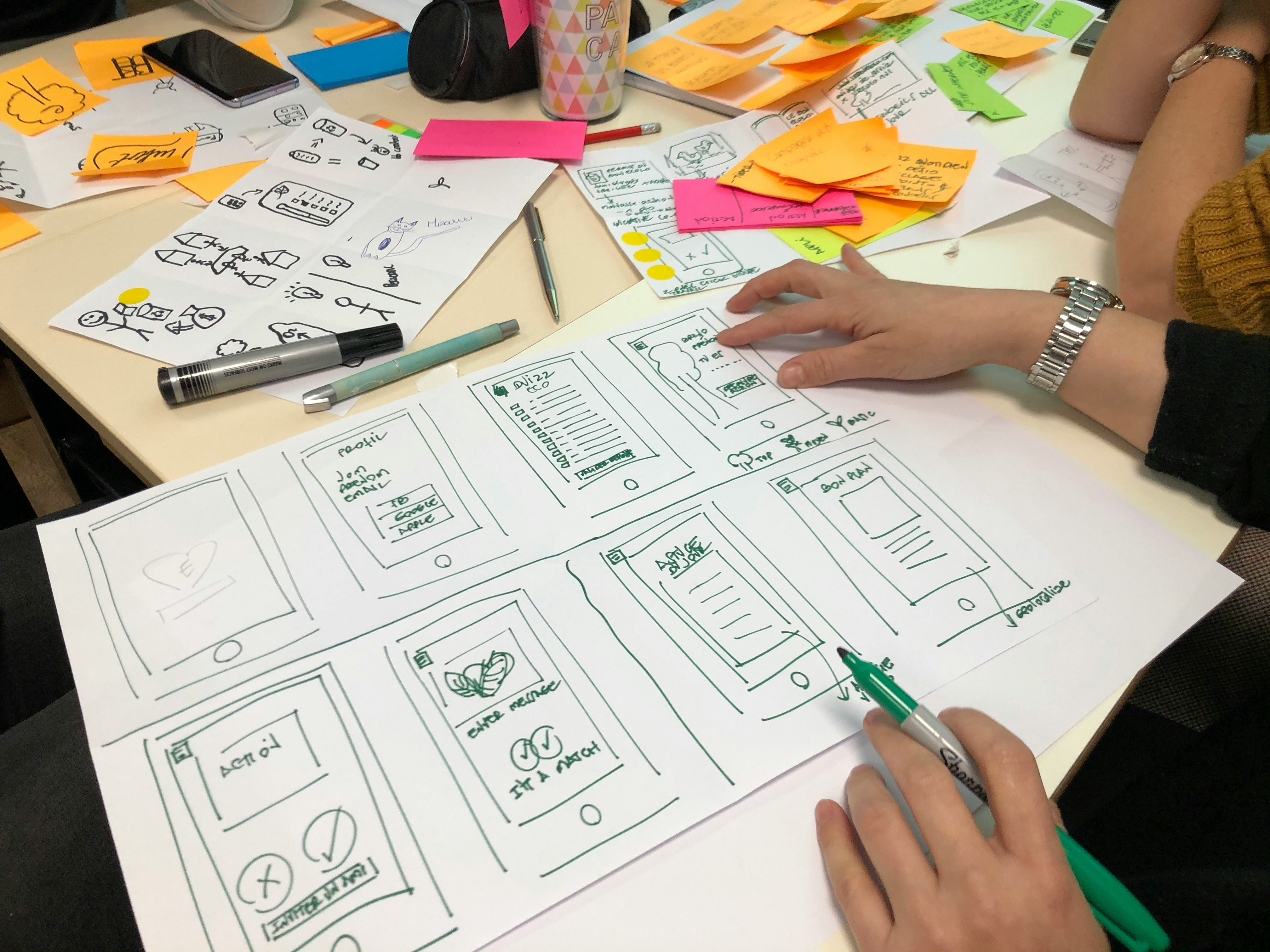 Hand sketching mobile app wireframes on paper during a design session